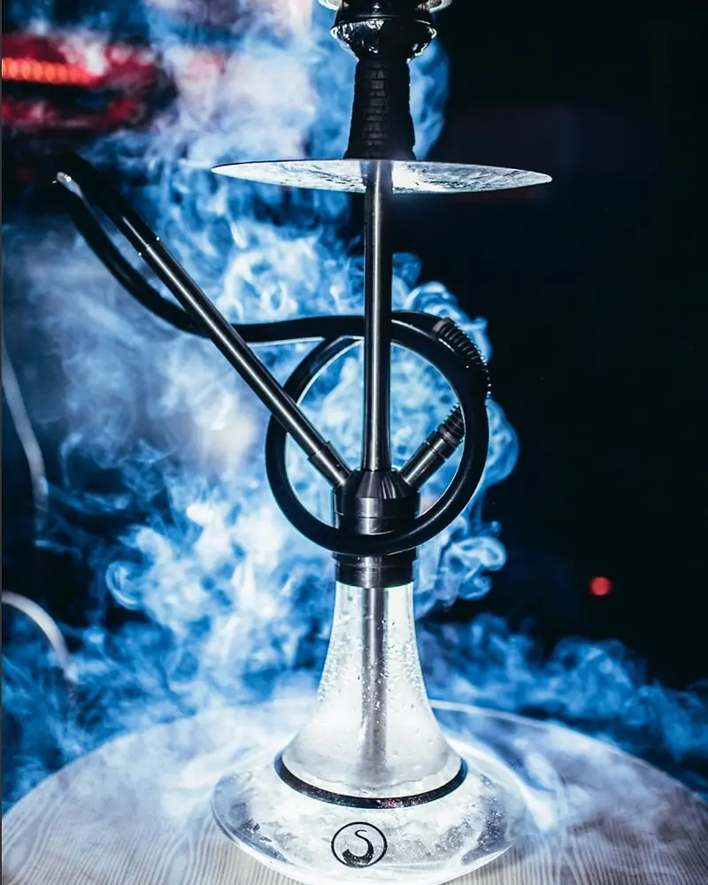 Hookah premium Cyril Premium envuelta en humo azul en un lounge de Cancún